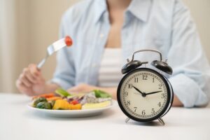 Intermittent Fasting Concept - Woman Eating With Clock