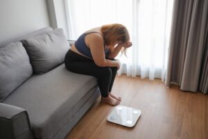 Woman Stressed on Couch Next to Scale